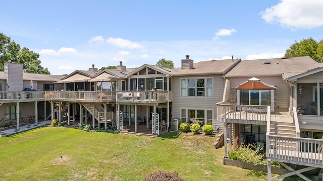 back of house featuring a lawn, a sunroom, and a deck