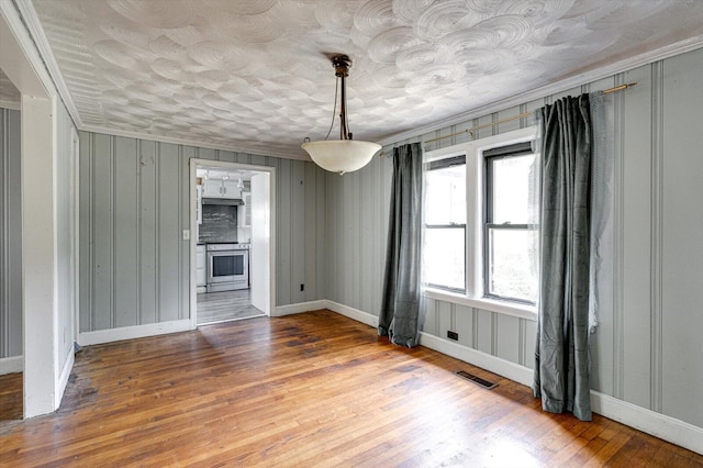 empty room featuring ornamental molding and hardwood / wood-style floors