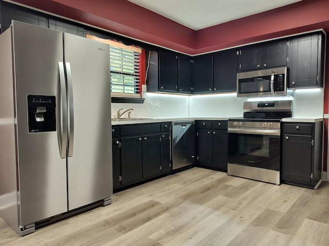 kitchen with appliances with stainless steel finishes, sink, and light hardwood / wood-style floors