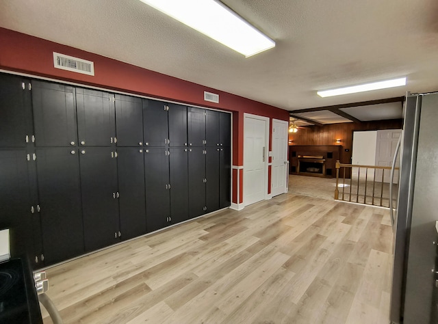 interior space with beamed ceiling, ceiling fan, a textured ceiling, and light wood-type flooring