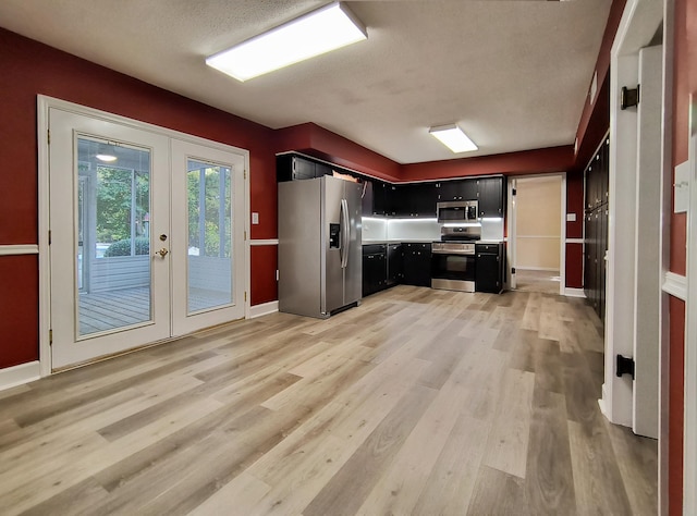 kitchen with french doors, stainless steel appliances, light hardwood / wood-style flooring, and a textured ceiling