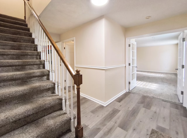 stairs with wood-type flooring and french doors