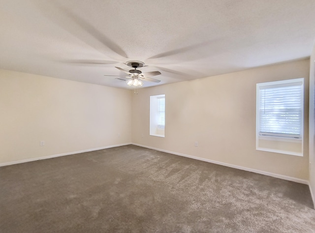 spare room with ceiling fan, a healthy amount of sunlight, and dark colored carpet