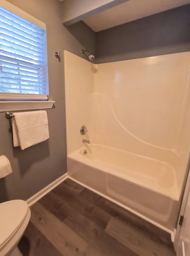 bathroom featuring hardwood / wood-style flooring,  shower combination, and toilet