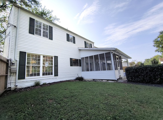 back of property with a sunroom and a yard