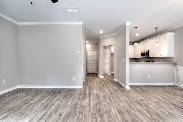 kitchen with crown molding, white cabinetry, hardwood / wood-style floors, and kitchen peninsula