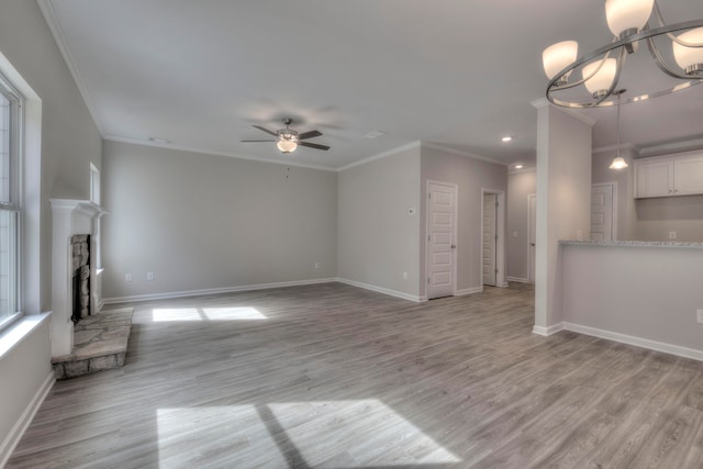 unfurnished living room featuring light wood-type flooring, ceiling fan with notable chandelier, a fireplace, and crown molding