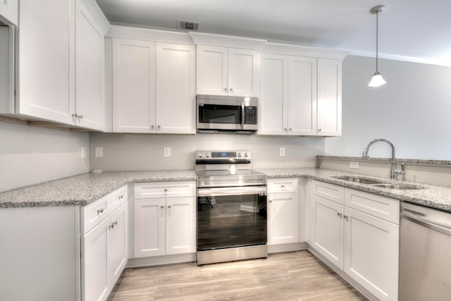 kitchen with appliances with stainless steel finishes, hanging light fixtures, sink, light stone counters, and white cabinets