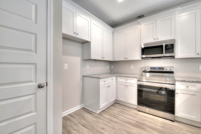 kitchen with white cabinets, appliances with stainless steel finishes, light stone countertops, and light hardwood / wood-style flooring