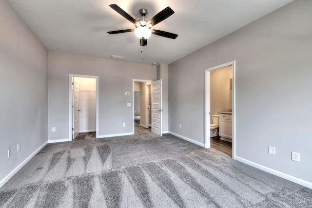 unfurnished bedroom featuring a spacious closet, ceiling fan, a closet, ensuite bathroom, and light colored carpet