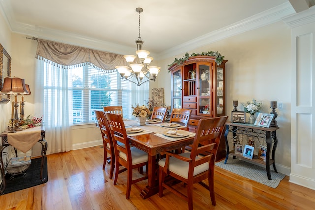 dining area with ornamental molding, light hardwood / wood-style flooring, and an inviting chandelier