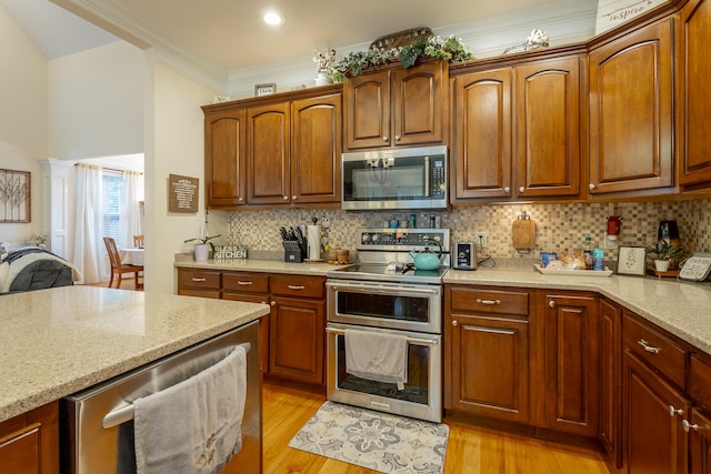 kitchen with backsplash, light wood-type flooring, light stone counters, stainless steel appliances, and ornamental molding