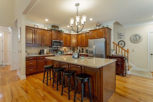 kitchen featuring an island with sink, light hardwood / wood-style flooring, stainless steel appliances, and a chandelier