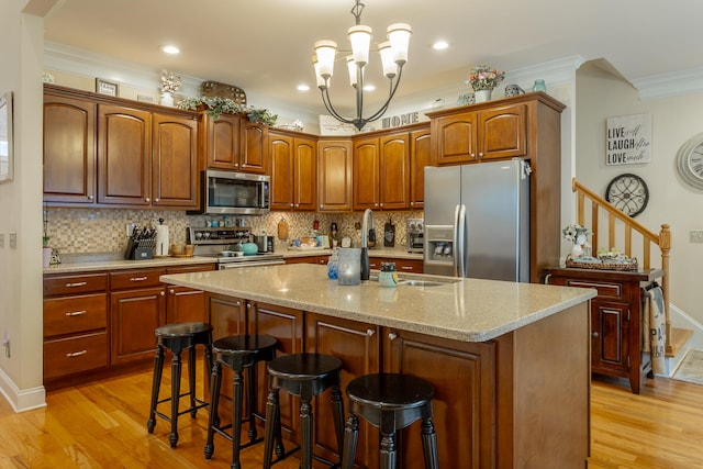 kitchen featuring an island with sink, stainless steel appliances, a notable chandelier, and light wood-type flooring