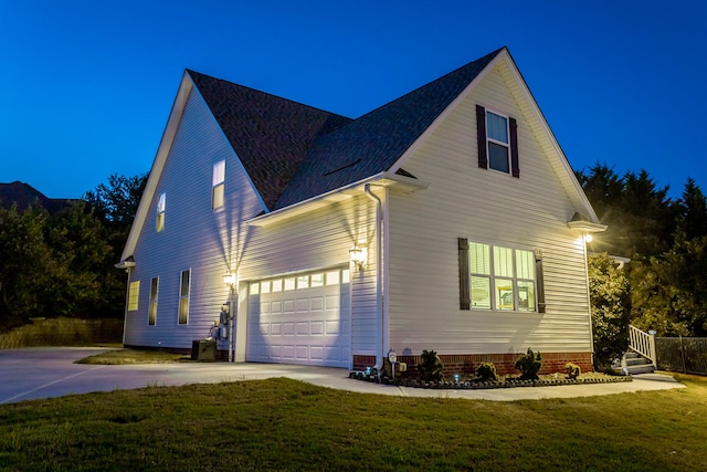 property exterior at night featuring a yard and a garage