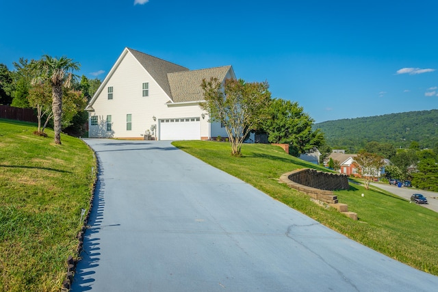 view of side of home with a yard, a garage, and a mountain view