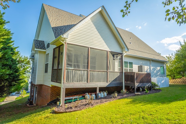 rear view of property featuring a lawn and a sunroom