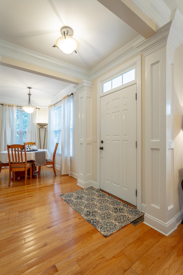 entryway with crown molding, light hardwood / wood-style flooring, and decorative columns