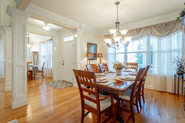 dining room with ornamental molding, a chandelier, ornate columns, and light hardwood / wood-style floors