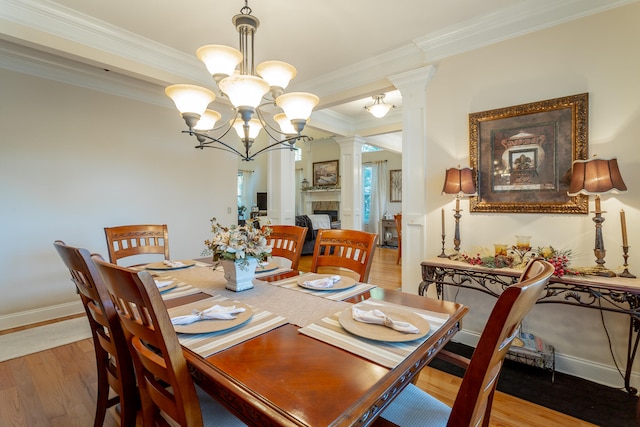 dining space featuring hardwood / wood-style floors, decorative columns, crown molding, and a notable chandelier