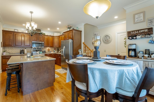 kitchen featuring a kitchen island with sink, appliances with stainless steel finishes, light hardwood / wood-style flooring, and an inviting chandelier