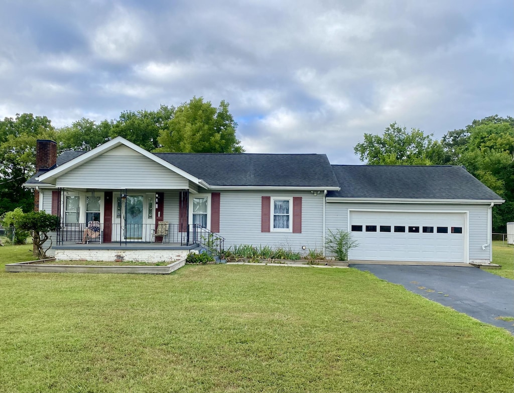 ranch-style home featuring a garage, a front lawn, and covered porch