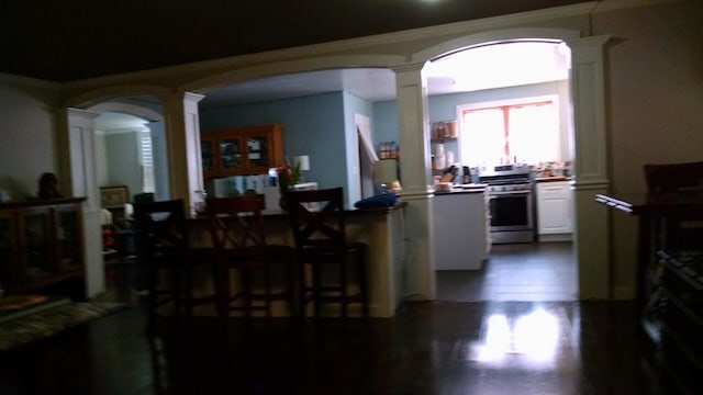 kitchen with stainless steel range oven, dark hardwood / wood-style floors, white cabinetry, and ornate columns