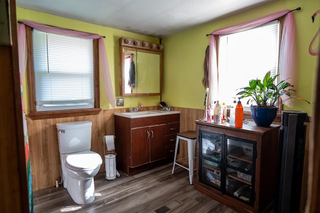 bathroom featuring vanity, toilet, hardwood / wood-style floors, and wooden walls