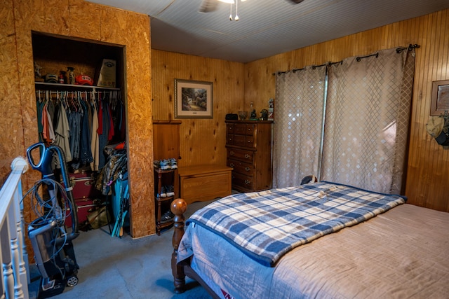 carpeted bedroom with a closet, ceiling fan, and wooden walls