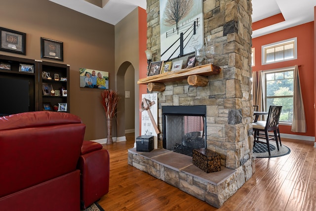 living room featuring a high ceiling, a fireplace, and hardwood / wood-style flooring