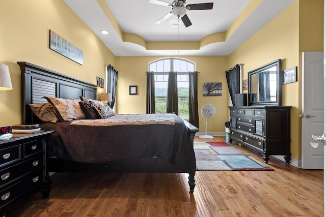 bedroom featuring a raised ceiling, hardwood / wood-style floors, and ceiling fan