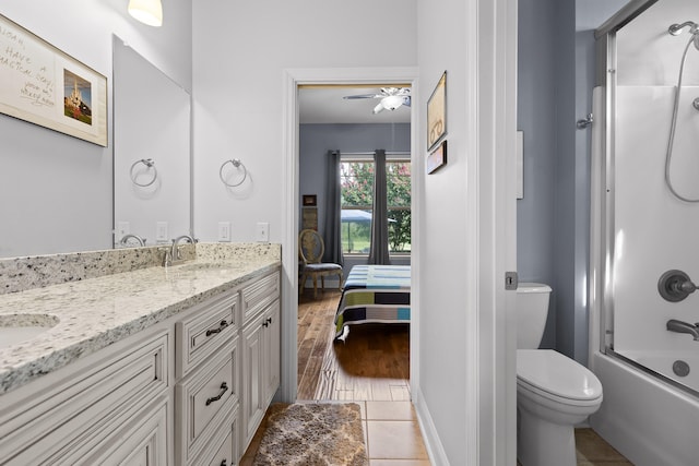 full bathroom with vanity, wood-type flooring, shower / bath combination with glass door, ceiling fan, and toilet