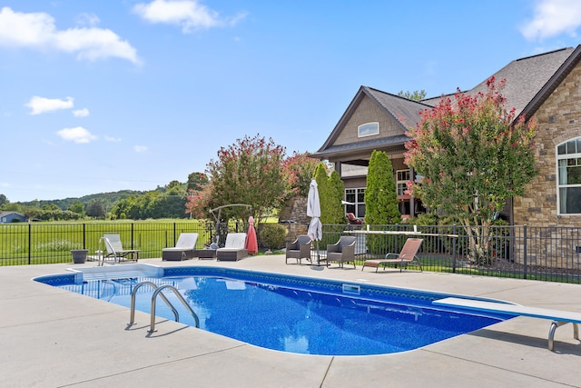 view of pool featuring a diving board and a patio