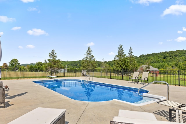 view of pool with a patio and a diving board