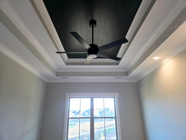 interior details featuring ceiling fan, a raised ceiling, and crown molding