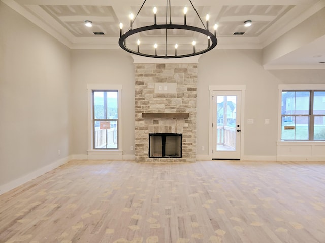 unfurnished living room featuring a towering ceiling, a fireplace, ornamental molding, a chandelier, and light wood-type flooring