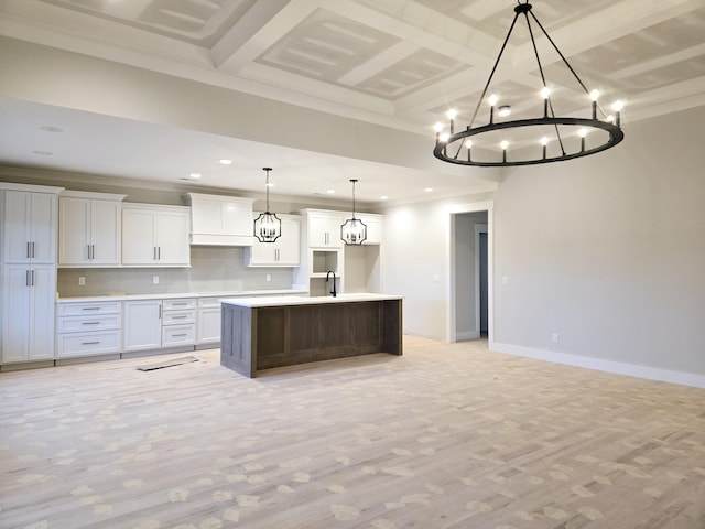 kitchen with white cabinetry, an island with sink, tasteful backsplash, sink, and hanging light fixtures