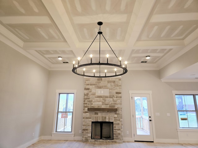 unfurnished living room featuring coffered ceiling, beam ceiling, and a stone fireplace