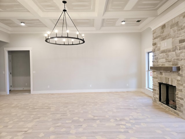 unfurnished living room featuring light wood-type flooring, coffered ceiling, a stone fireplace, and beam ceiling