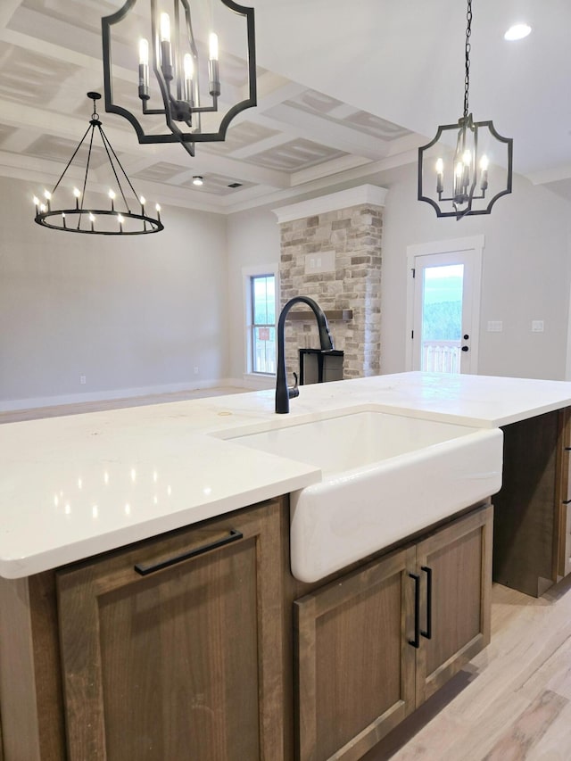 kitchen with a center island, light hardwood / wood-style floors, a chandelier, hanging light fixtures, and sink