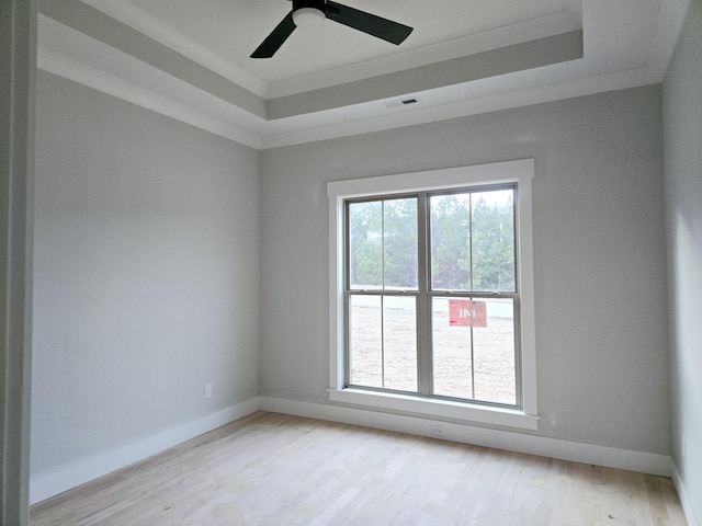 unfurnished room with light hardwood / wood-style floors, ornamental molding, a raised ceiling, and ceiling fan