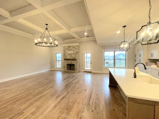 kitchen featuring sink, a kitchen island with sink, pendant lighting, and an inviting chandelier