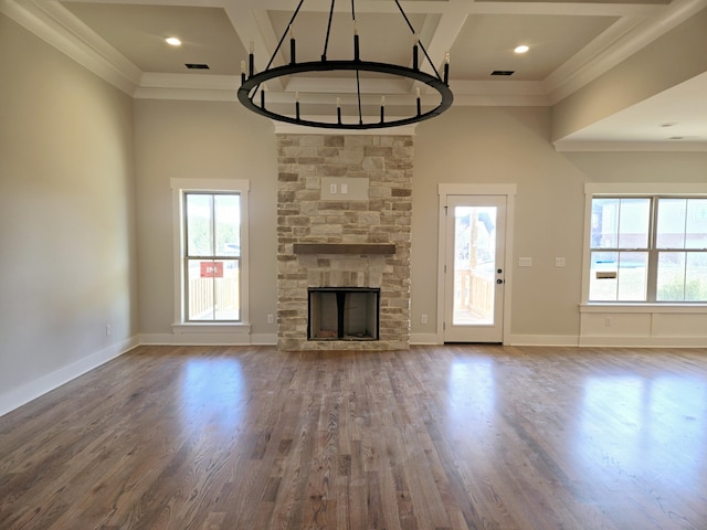 unfurnished living room featuring crown molding, coffered ceiling, a stone fireplace, and hardwood / wood-style floors