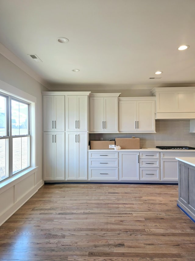 kitchen with crown molding, light hardwood / wood-style floors, decorative backsplash, and white cabinets