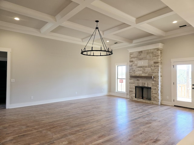 unfurnished living room featuring plenty of natural light, coffered ceiling, a chandelier, and hardwood / wood-style floors