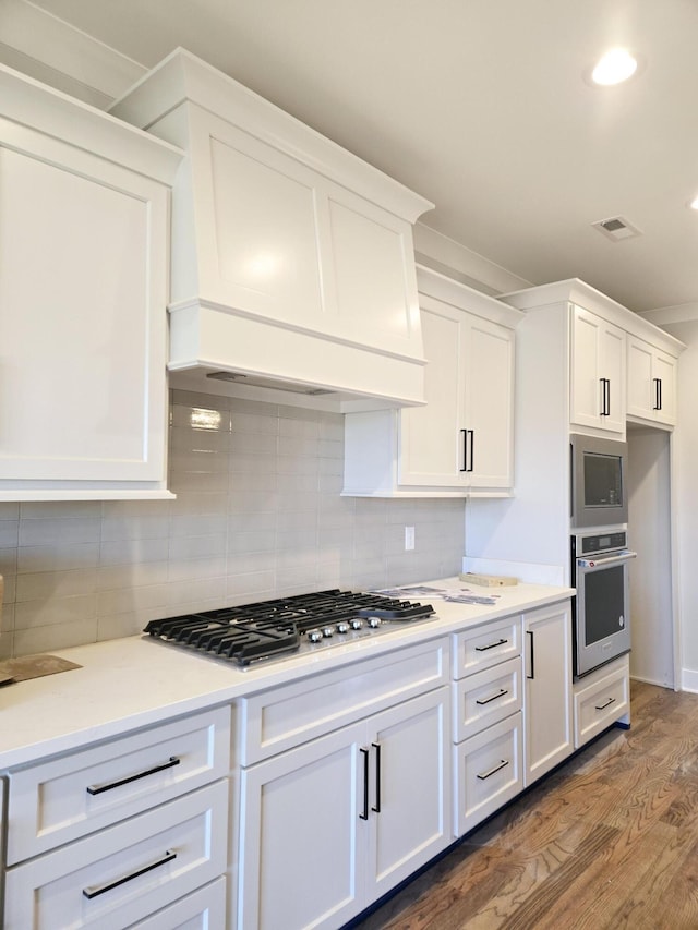 kitchen featuring stainless steel appliances, white cabinetry, backsplash, and dark hardwood / wood-style flooring