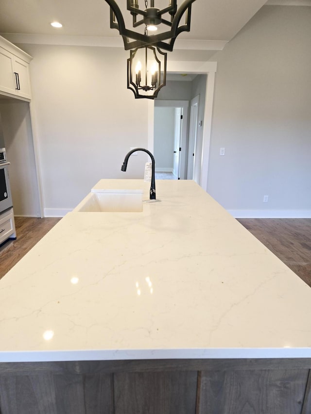 kitchen featuring white cabinetry, ornamental molding, light stone countertops, and sink