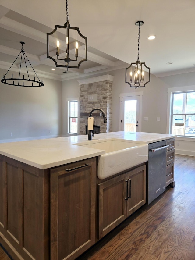 kitchen with sink, crown molding, dark wood-type flooring, a kitchen island with sink, and hanging light fixtures