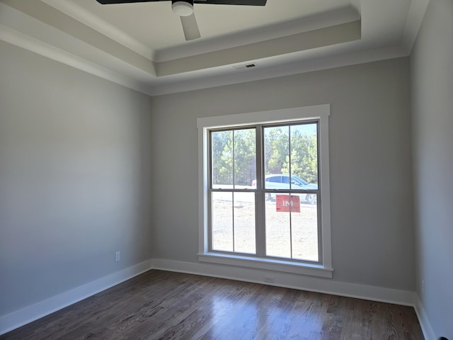 spare room with a raised ceiling, crown molding, dark wood-type flooring, and ceiling fan