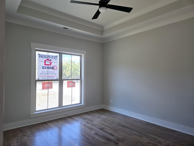 unfurnished room featuring dark wood-type flooring, ceiling fan, and a tray ceiling